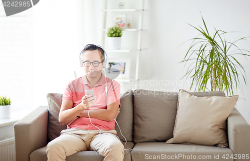 Image of man with smartphone and headphones at home
