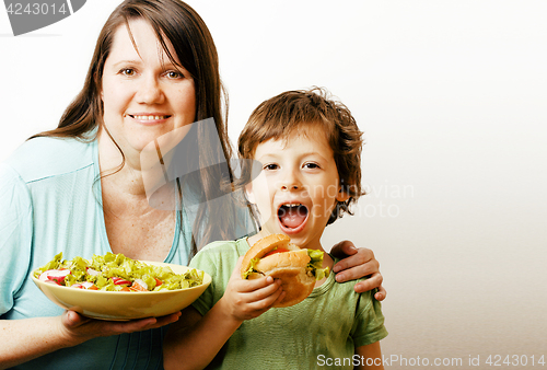 Image of mature woman holding salad and little cute boy with hamburger te