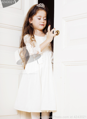 Image of little cute girl at home, opening door well-dressed in white dre