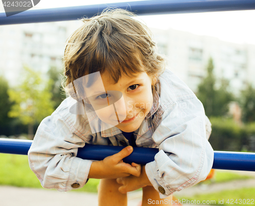 Image of little cute boy playing on playground, hanging on gymnastic ring