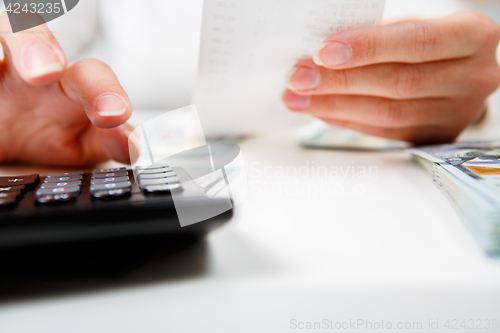 Image of savings, finances, economy and home concept - close up of hands with calculator counting money and making notes at home