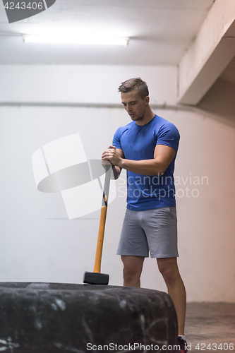 Image of man workout with hammer and tractor tire