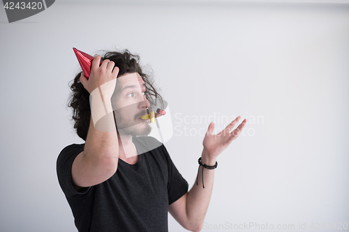 Image of Portrait of a man in party hat blowing in whistle