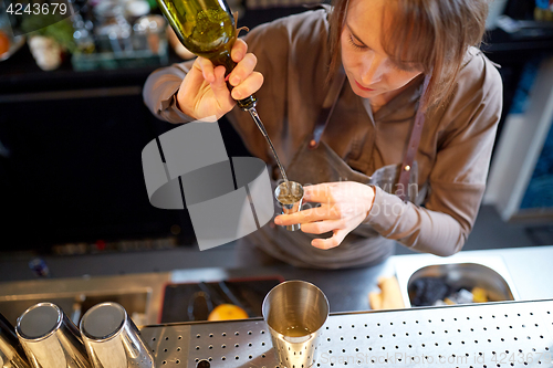 Image of bartender pouring alcohol into jigger at bar