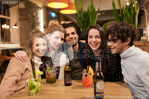 Image of happy friends with drinks at bar or cafe