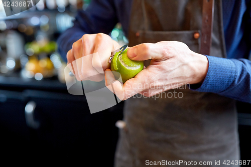 Image of bartender removing peel from lime at bar