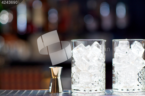 Image of glasses with ice and jigger on bar counter