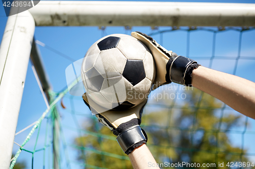 Image of goalkeeper with ball at football goal on field