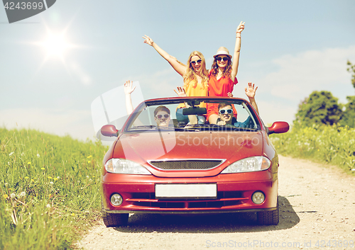 Image of happy friends driving in cabriolet car at country