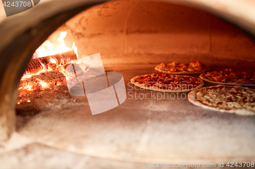 Image of pizza baking in oven at pizzeria