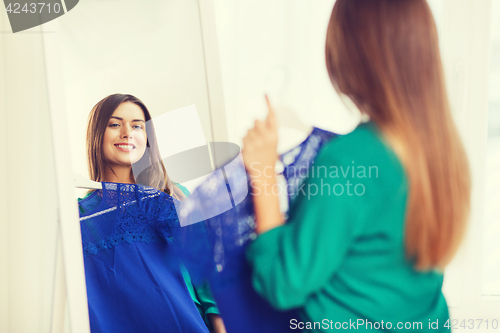 Image of happy woman choosing clothes at home wardrobe