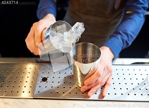 Image of bartender with ice and shaker at cocktail bar