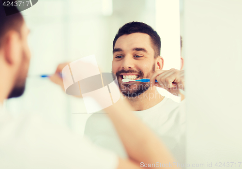 Image of man with toothbrush cleaning teeth at bathroom