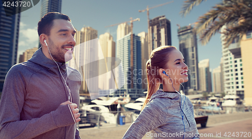 Image of happy couple with earphones running in city