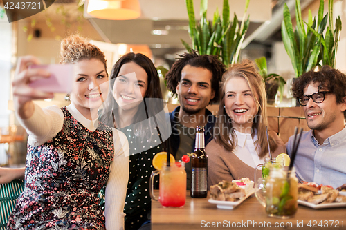 Image of friends taking selfie by smartphone at bar or cafe