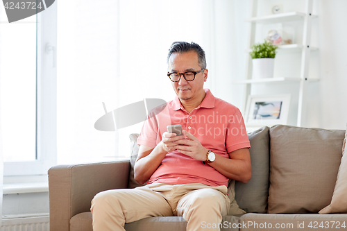 Image of man with smartphone sitting on sofa at home