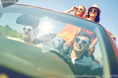 Image of happy friends driving in cabriolet car