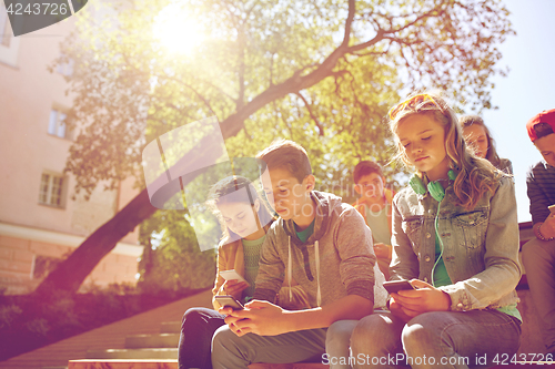 Image of group of teenage friends with smartphones outdoors