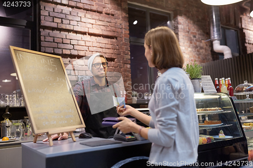 Image of happy barman and woman paying money at cafe