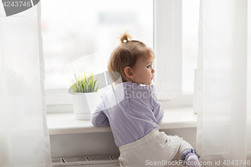 Image of lovely little girl at home window