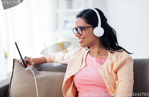Image of happy woman with tablet pc and headphones at home
