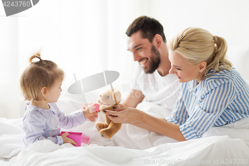 Image of happy family with gift box in bed at home