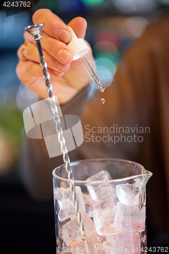 Image of bartender adding essence to cocktail glass at bar