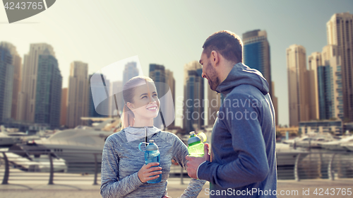 Image of smiling couple with bottles of water in city