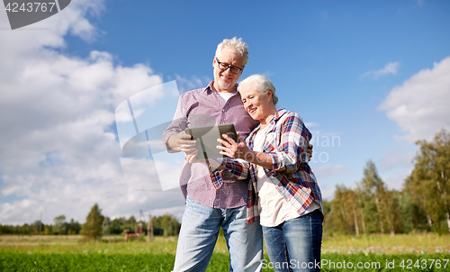 Image of happy senior couple with tablet pc at summer farm