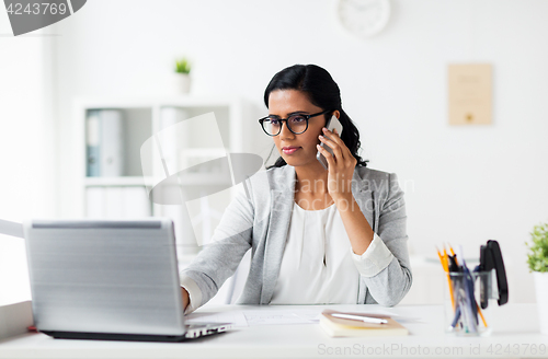 Image of businesswoman with laptop and smartphone at office