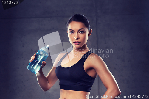 Image of woman drinking water from bottle in gym