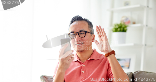 Image of happy man having video call on smartphone at home
