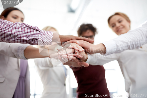 Image of happy business team with hands on top at office