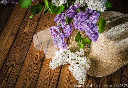 Image of Still-life with a bouquet of lilacs and a straw hat, close-up