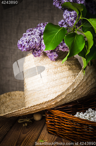 Image of Still-life with a bouquet of lilacs and a straw hat, close-up