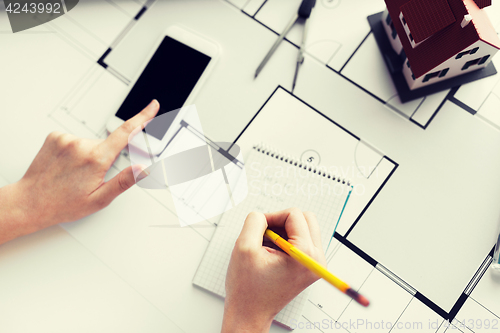 Image of close up of hands with blueprint and smarphone