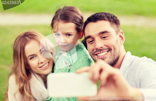 Image of happy family taking selfie by smartphone outdoors