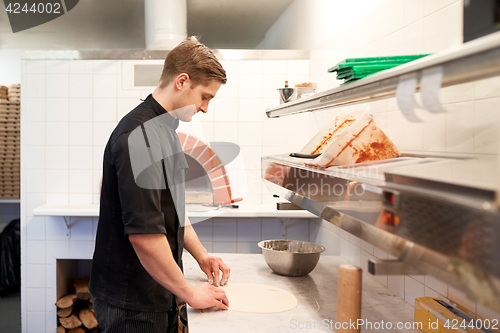 Image of chef preparing pizza dough in kitchen at pizzeria
