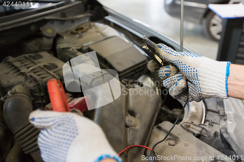 Image of auto mechanic man with cleats charging battery