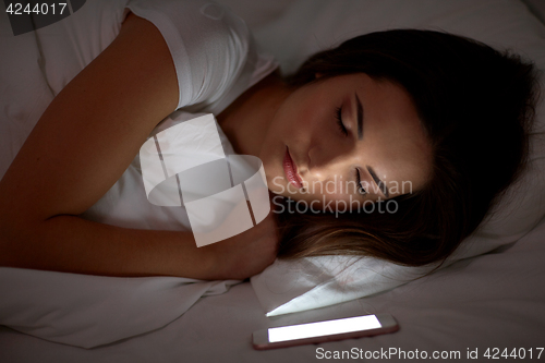 Image of woman with smartphone sleeping in bed at night