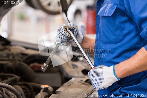 Image of mechanic man with wrench repairing car at workshop