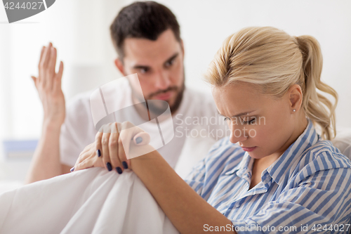 Image of unhappy couple having conflict in bed at home