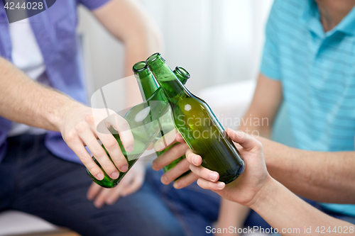 Image of close up of friends clinking beer bottles at home