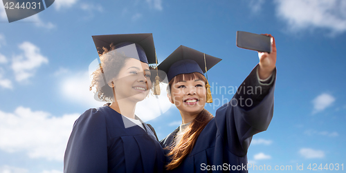 Image of students taking selfie by smartphone over blue sky