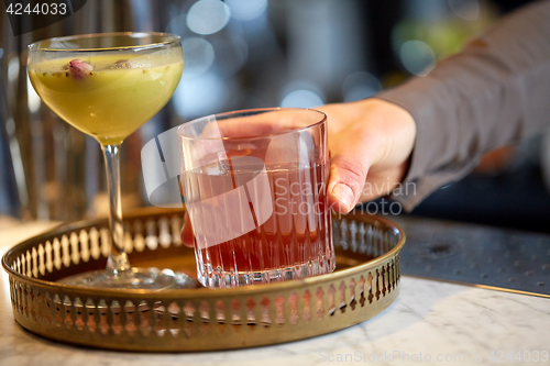 Image of bartender with glasses of cocktails at bar