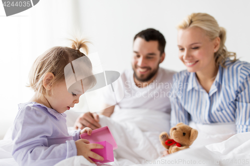 Image of happy family with gift box in bed at home