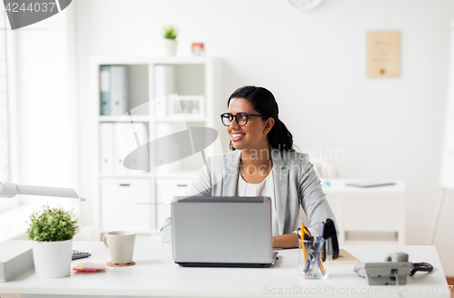 Image of happy smiling businesswoman with laptop at office
