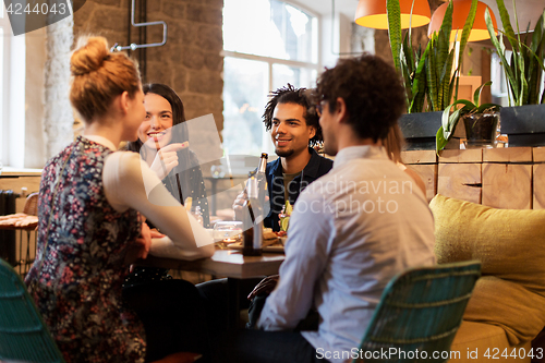 Image of happy friends eating and drinking at bar or cafe