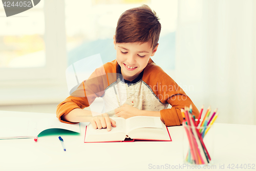 Image of smiling, student boy reading book at home