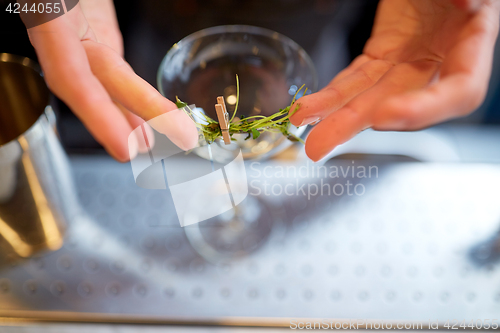 Image of bartender decorating glass of cocktail at bar